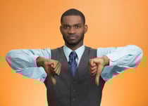 Closeup portrait unhappy, angry, mad, annoyed, grumpy man giving thumbs down gesture, looking with negative facial expression disapproval isolated orange background. Human emotion hand sign, attitude