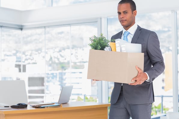 Businessman leaving his company while he is holding a box