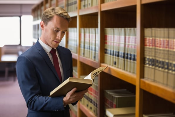 man in library reviewing law textbooks