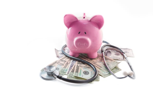 Piggy bank and stethoscope resting on pile of dollars on white background-1