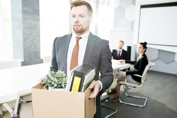 Young Businessman leaving his job with a box of things from his office